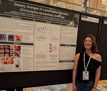 An accomplished undergraduate researcher stands beside her poster of results